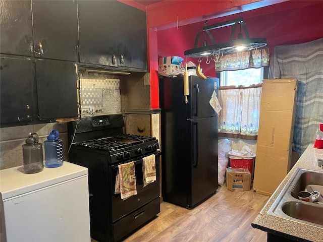 kitchen featuring tasteful backsplash, sink, light hardwood / wood-style flooring, and black appliances