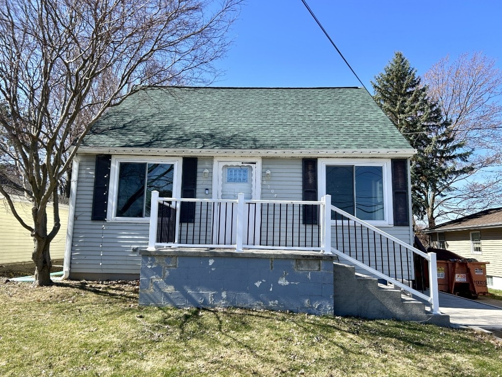 bungalow-style house with a front lawn and roof with shingles