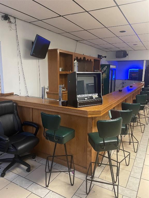 bar with light tile patterned floors and a drop ceiling