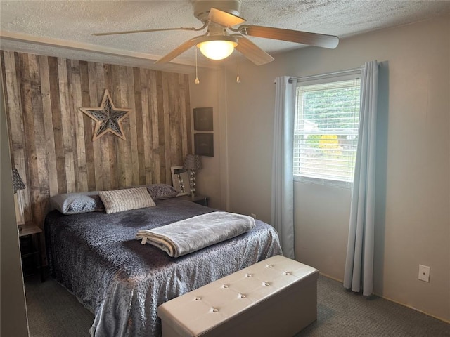 bedroom with a textured ceiling, wooden walls, ceiling fan, and carpet floors