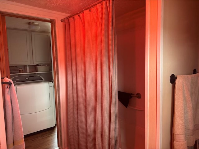 laundry room with a textured ceiling, cabinet space, wood finished floors, and washer / dryer