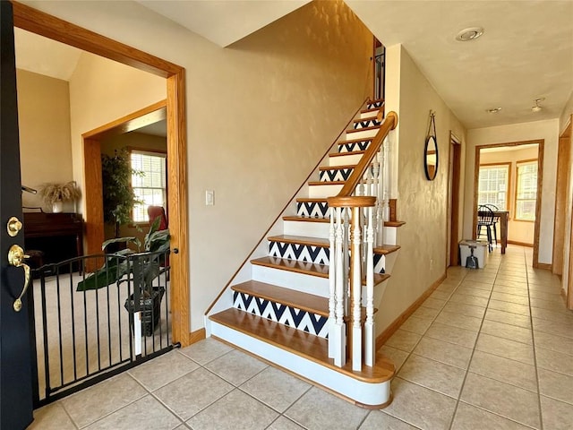 stairs featuring baseboards, plenty of natural light, and tile patterned flooring