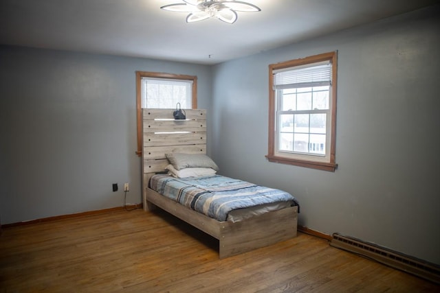 bedroom featuring a baseboard heating unit and hardwood / wood-style floors