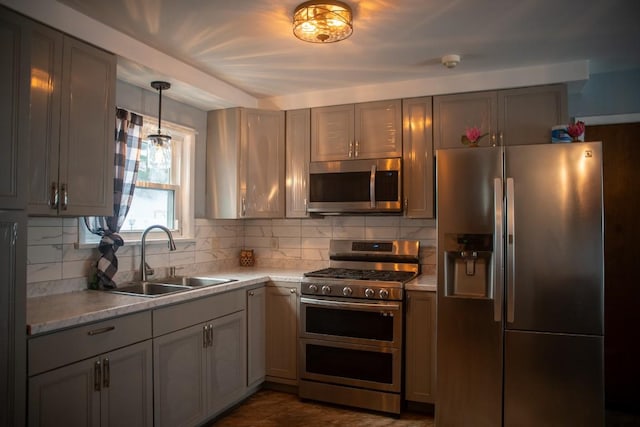 kitchen featuring sink, gray cabinetry, pendant lighting, stainless steel appliances, and backsplash