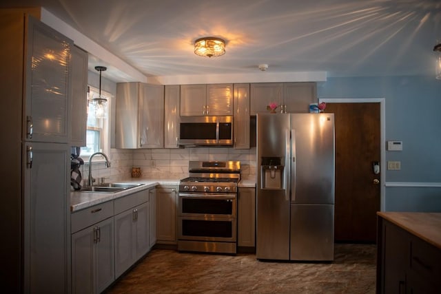 kitchen with tasteful backsplash, appliances with stainless steel finishes, sink, and pendant lighting