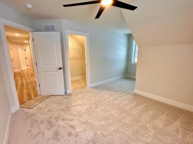 additional living space featuring ceiling fan, light carpet, and lofted ceiling