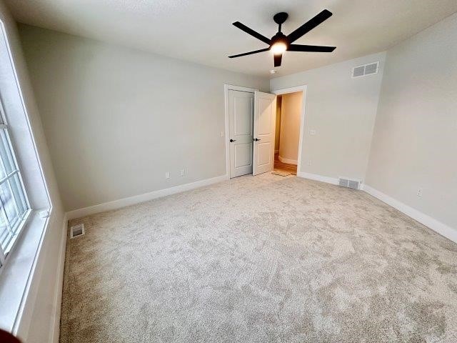 spare room featuring ceiling fan and light colored carpet