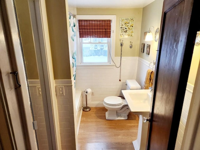 bathroom featuring sink, walk in shower, hardwood / wood-style floors, toilet, and tile walls