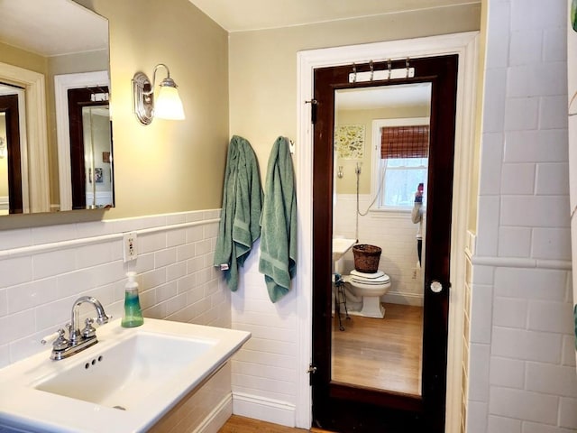 bathroom with toilet, sink, and tile walls