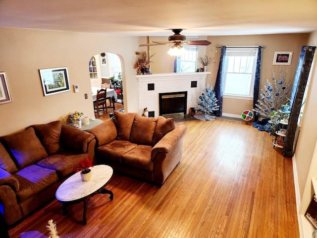 living room featuring a fireplace, light hardwood / wood-style flooring, and ceiling fan