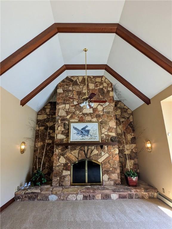 unfurnished living room with beam ceiling, ceiling fan, a baseboard radiator, a fireplace, and carpet