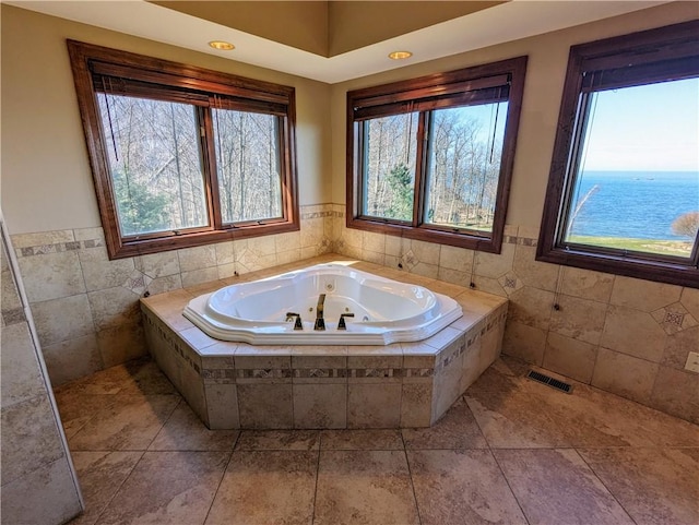 bathroom with tile patterned floors, a water view, and tiled bath