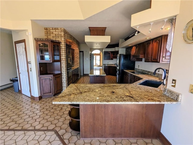 kitchen with kitchen peninsula, light stone counters, sink, and a breakfast bar