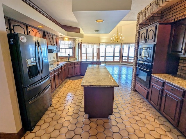 kitchen featuring a notable chandelier, a center island, black appliances, sink, and decorative light fixtures