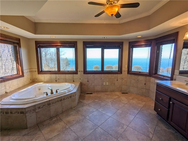 bathroom with vanity, ceiling fan, crown molding, a water view, and a relaxing tiled tub