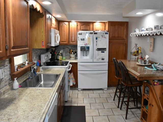 kitchen with light tile patterned floors, white appliances, tasteful backsplash, and sink