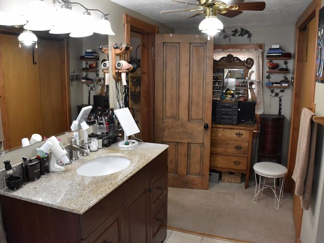 bathroom with a textured ceiling, ceiling fan, and sink