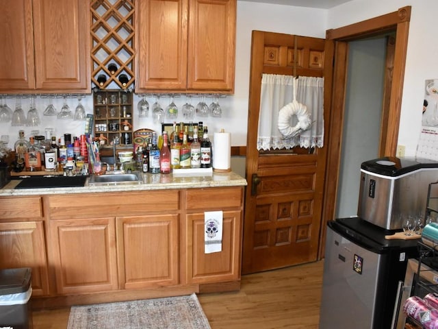 kitchen featuring light wood-type flooring, backsplash, refrigerator, and light stone counters