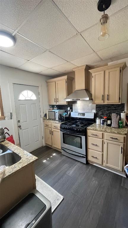 457 E 24th St, Erie, PA 16503 - kitchen featuring appliances with stainless steel finishes, wall chimney range hood, light countertops, dark wood-style flooring, and backsplash