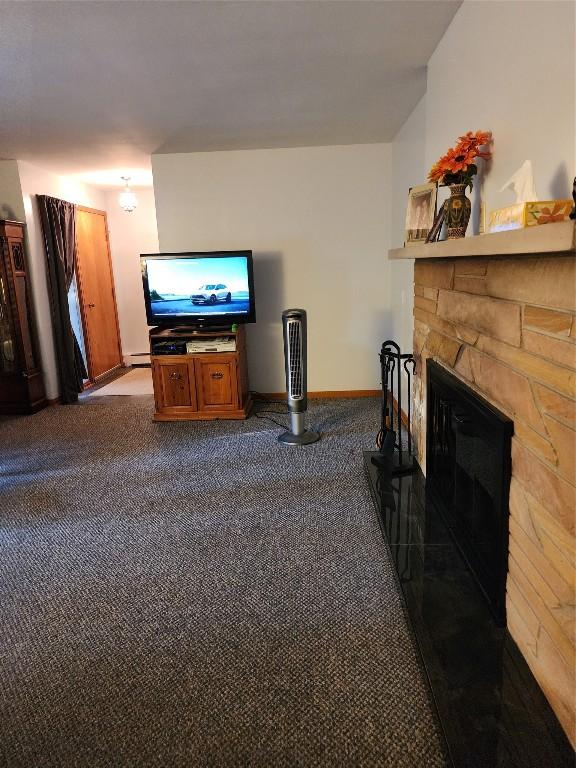 living room featuring a fireplace, carpet floors, and a baseboard radiator