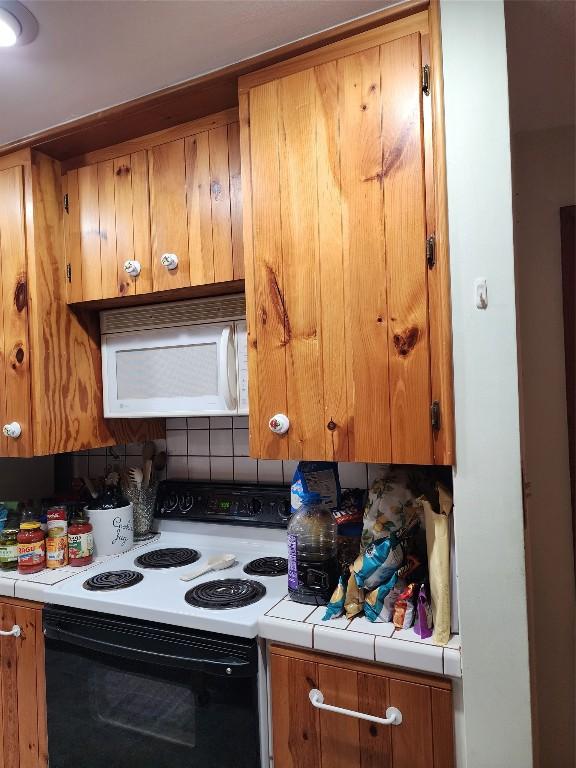 kitchen with range with electric cooktop, tile countertops, and tasteful backsplash