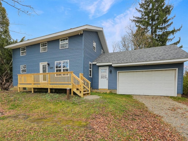 back of property with a deck, a lawn, and a garage