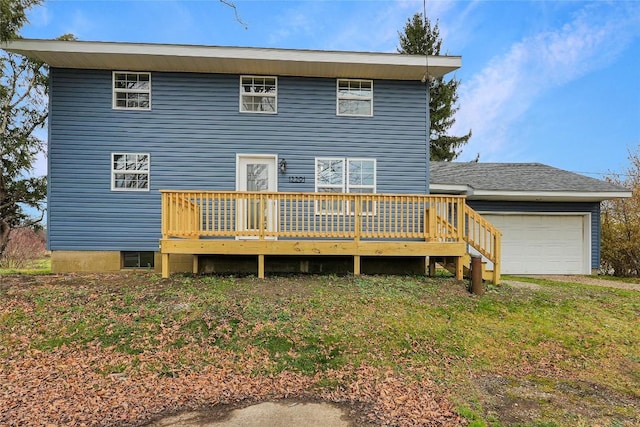 rear view of property featuring a garage, a deck, and a yard