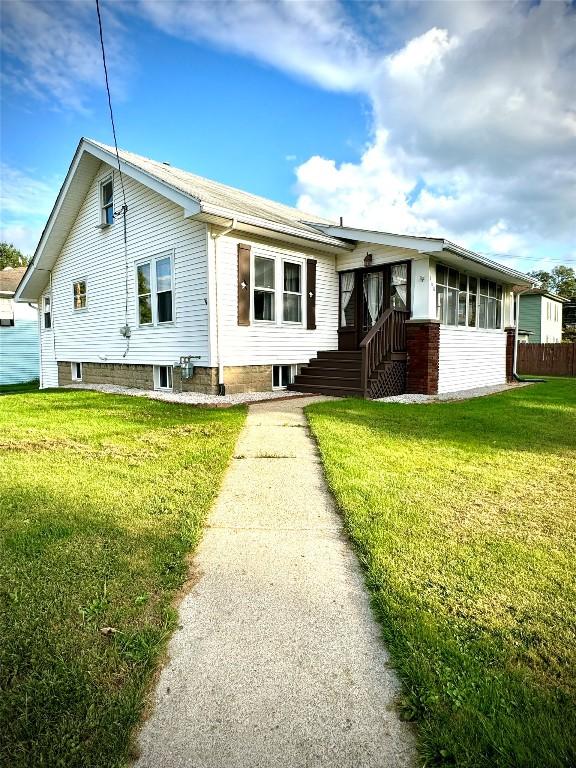 view of front of property featuring a sunroom and a front lawn