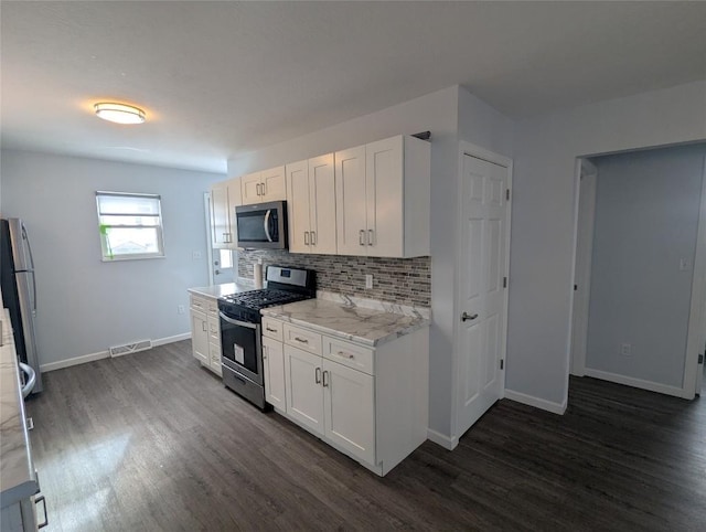 kitchen with white cabinetry, backsplash, stainless steel appliances, dark hardwood / wood-style floors, and light stone countertops