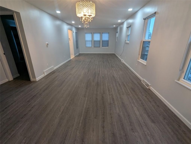 spare room with dark hardwood / wood-style flooring and a notable chandelier