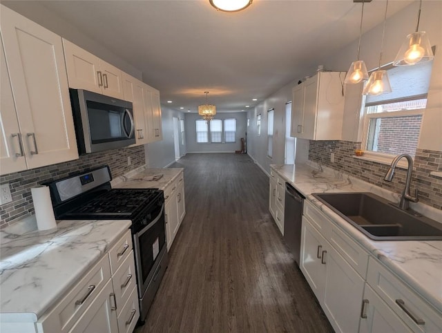 kitchen with stainless steel appliances, white cabinetry, sink, and decorative light fixtures