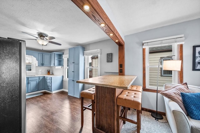 kitchen featuring a kitchen breakfast bar, open shelves, freestanding refrigerator, and blue cabinets