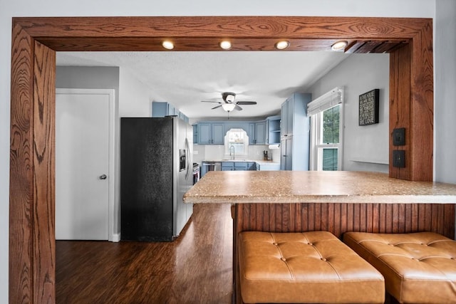 kitchen with blue cabinets, stainless steel appliances, a peninsula, dark wood-style flooring, and light countertops