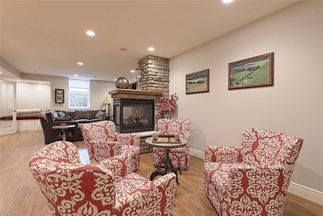 living room featuring a stone fireplace and light hardwood / wood-style flooring