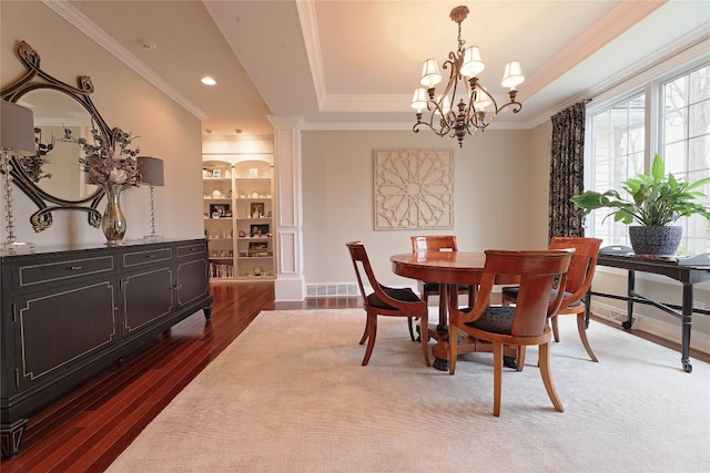 dining space featuring built in shelves, ornamental molding, dark wood-type flooring, and a chandelier