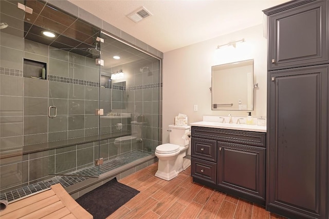 bathroom with vanity, toilet, and a shower with door