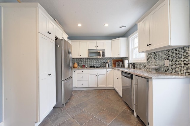 kitchen with appliances with stainless steel finishes, backsplash, white cabinetry, and sink