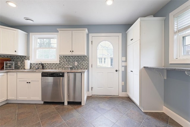 kitchen featuring white cabinets, stainless steel dishwasher, plenty of natural light, and sink