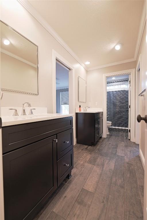 bathroom with wood-type flooring, vanity, toilet, and crown molding