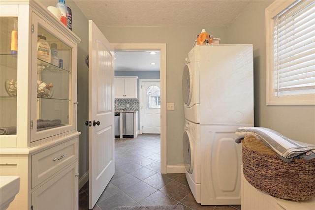 interior space featuring a textured ceiling, dark tile patterned floors, and stacked washer and clothes dryer