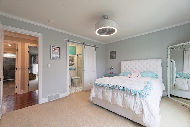 carpeted bedroom with a barn door, ensuite bathroom, and crown molding