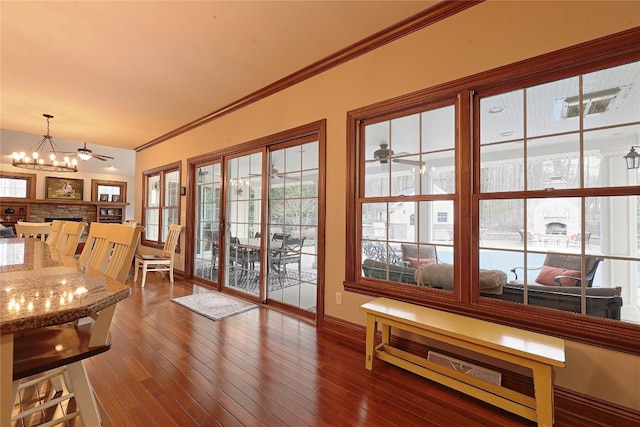 entryway with ceiling fan with notable chandelier, ornamental molding, and dark wood-type flooring