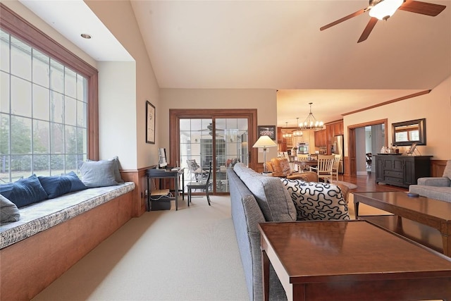 carpeted living room featuring ceiling fan with notable chandelier and vaulted ceiling