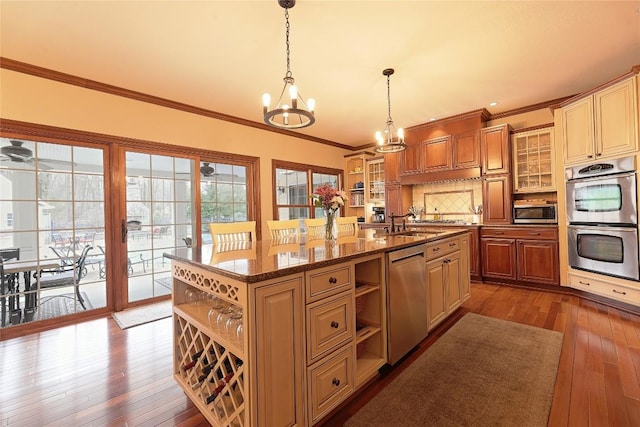 kitchen with tasteful backsplash, stainless steel appliances, a center island with sink, an inviting chandelier, and hanging light fixtures