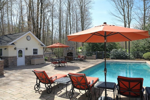 view of swimming pool featuring an outdoor structure, a patio area, and an outdoor stone fireplace