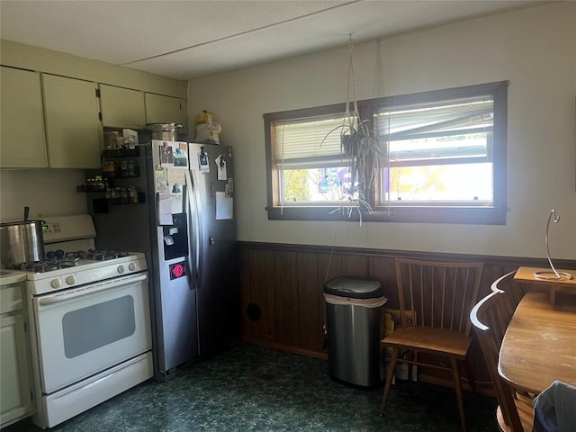 kitchen featuring wooden walls, stainless steel fridge, and white range with gas cooktop