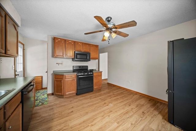 kitchen with ceiling fan, a textured ceiling, light hardwood / wood-style floors, and black appliances