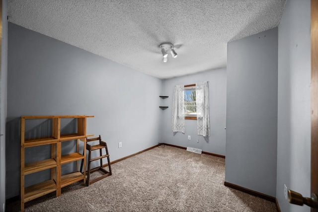 carpeted empty room featuring a textured ceiling