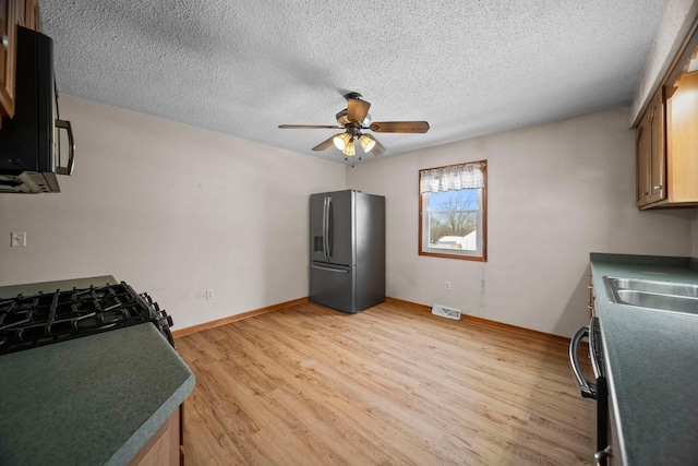 kitchen with ceiling fan, sink, stainless steel fridge, and light hardwood / wood-style floors