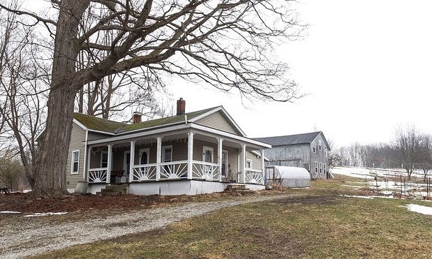 view of side of home featuring covered porch, driveway, and a chimney